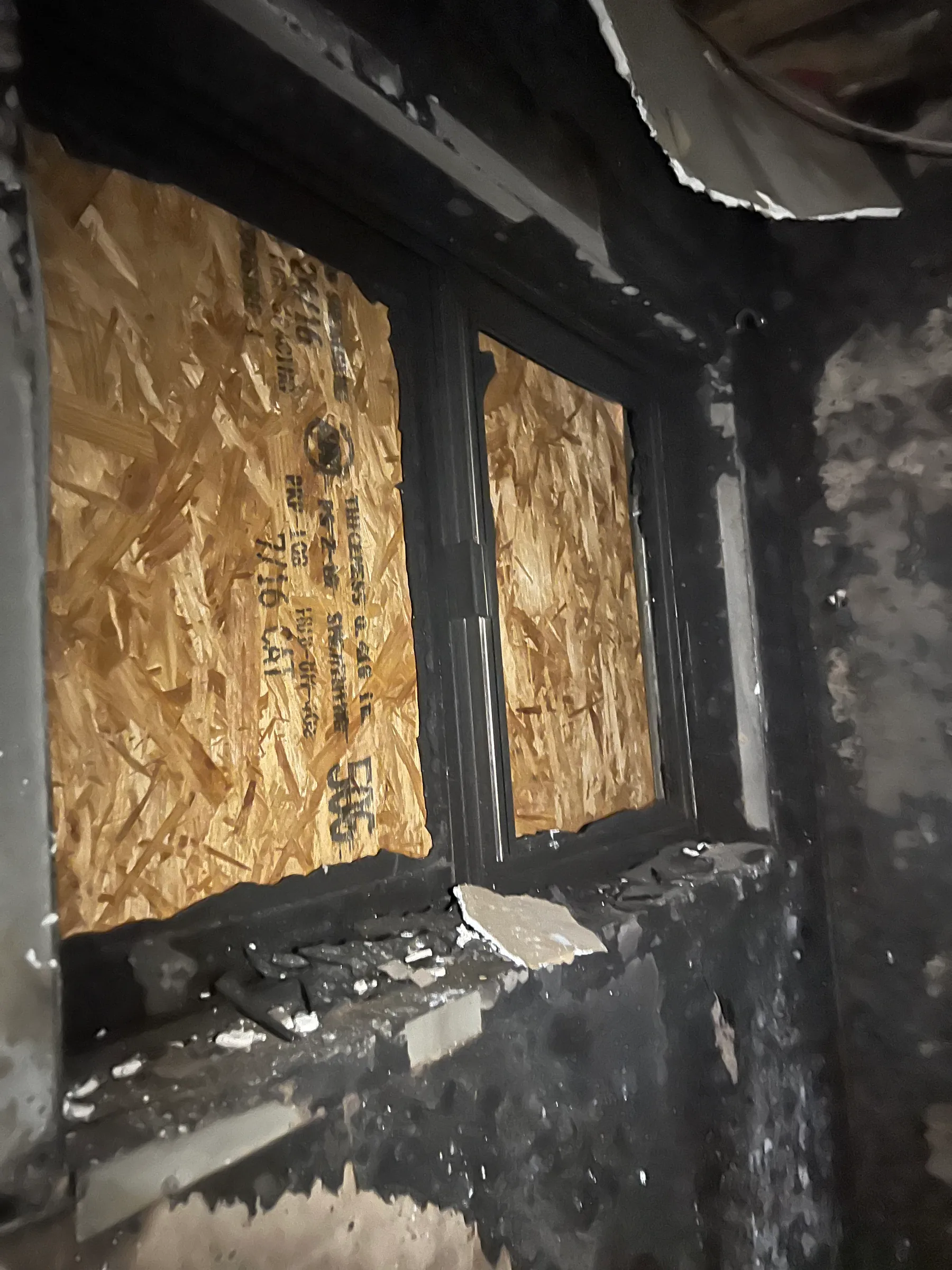 Boarded window and charred interior wall after a residential fire