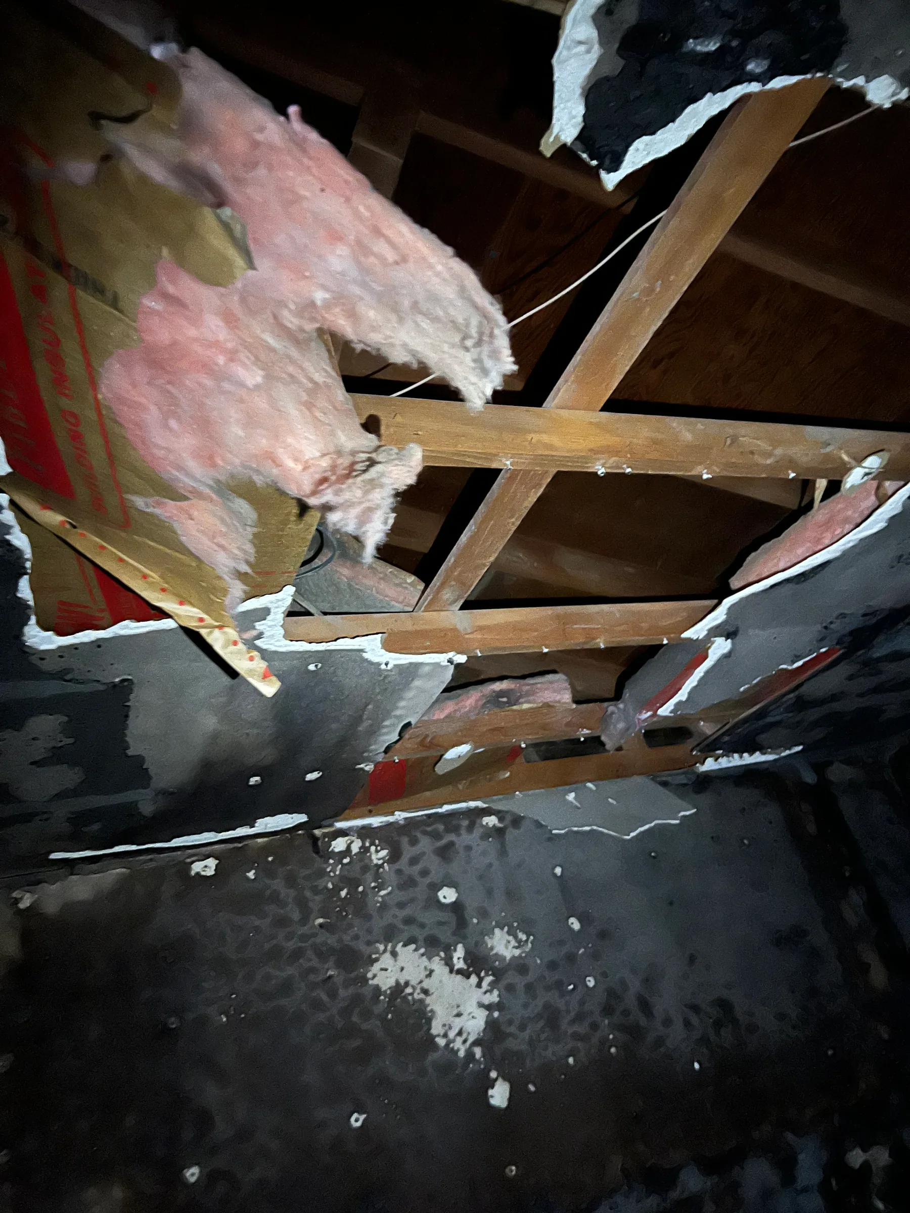 Open ceiling with burned drywall and exposed insulation after fire damage