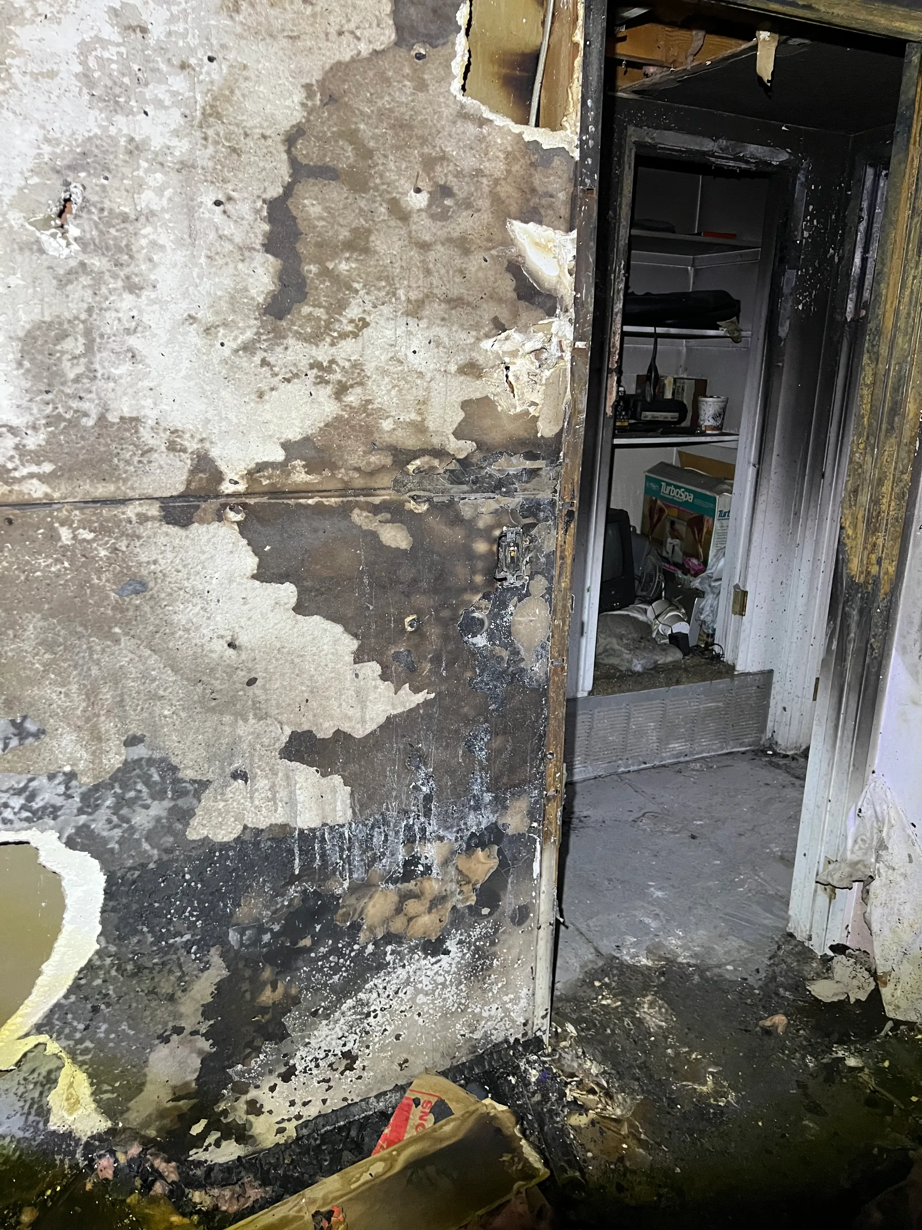 Room cleared for pack-out after fire damage, with charred wall visible
