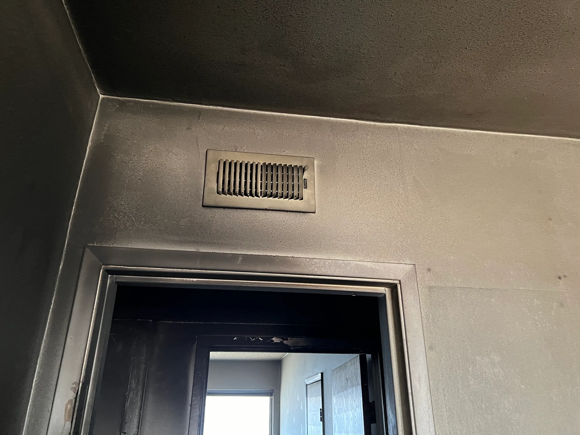 Hallway ceiling and vent covered with soot after smoke damage
