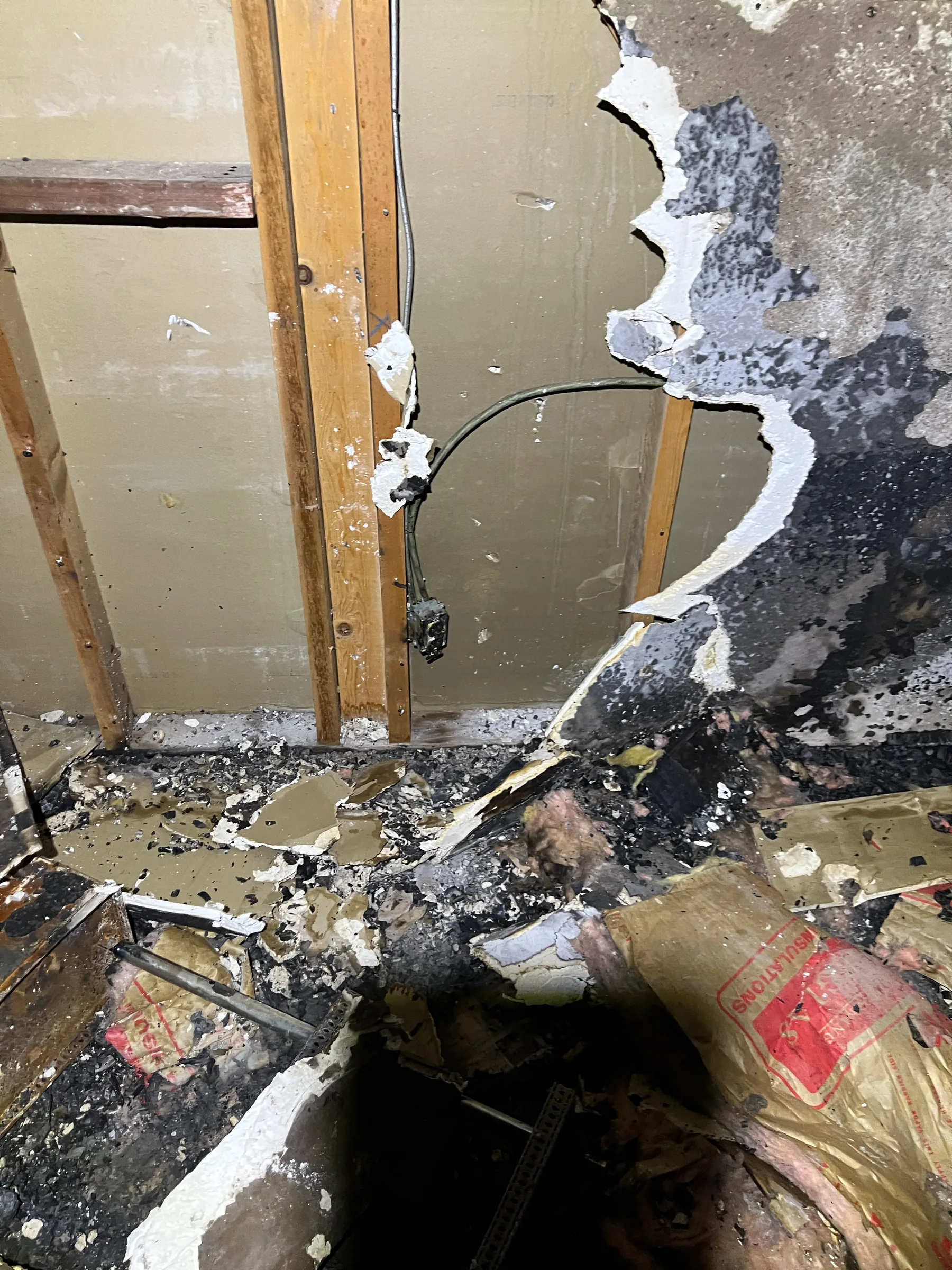 Open wall cavity with burn patterns and smoke damage after fire cleanup
