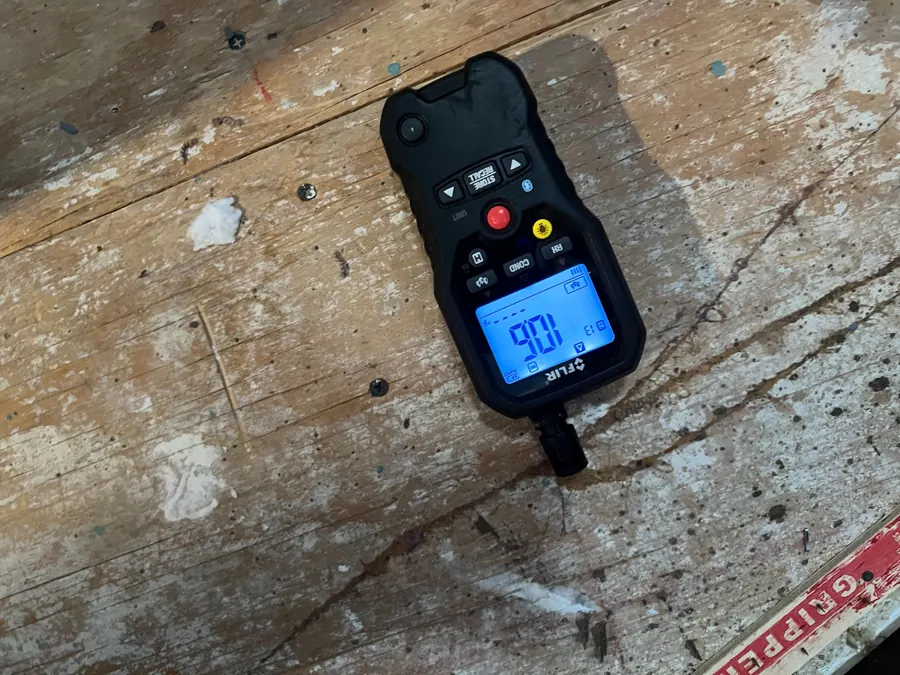 Moisture meter resting on the exposed plywood subfloor during drying