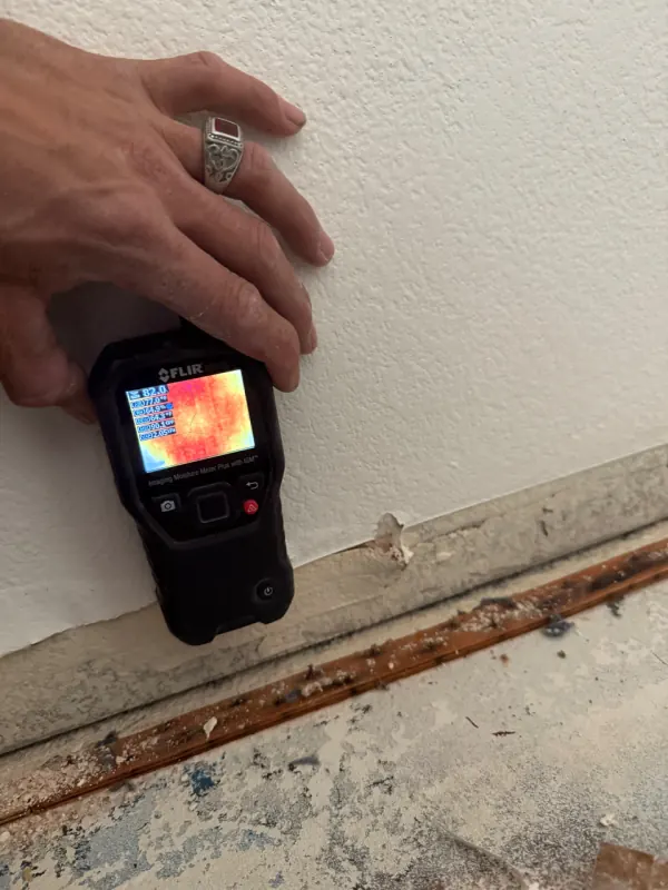 Baseboard removal exposing wet wall cavity from an appliance leak in Henderson