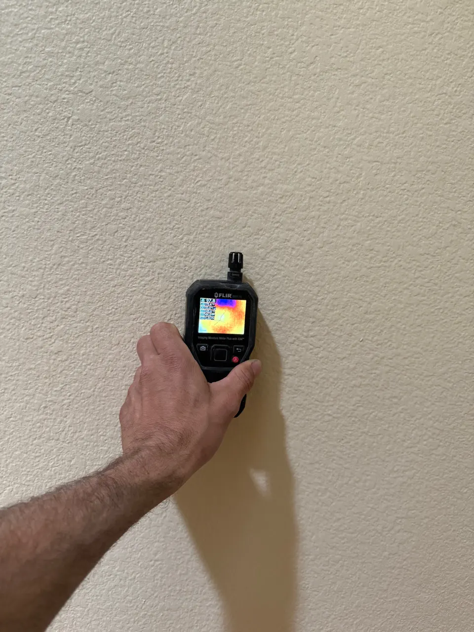 Technician using a thermal imaging camera to document a wall during a water damage inspection in Las Vegas