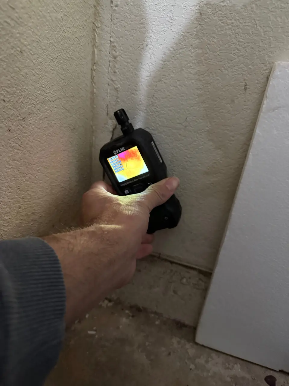 Technician scanning a wall with a thermal imaging moisture meter during a mold inspection